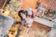 A woman dressed as a cat sitting on a chair in front of a Christmas tree.