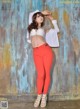 A woman in a white top and red pants posing for a picture.