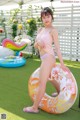 A woman in a pink bathing suit sitting on an inflatable ring.