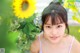 A young woman standing in front of a sunflower.