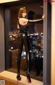 A woman in a black top and black pants standing in front of a window.