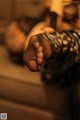 A close up of a woman's feet in black stockings and bracelets.