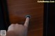 A person is pressing a button on a wooden door.